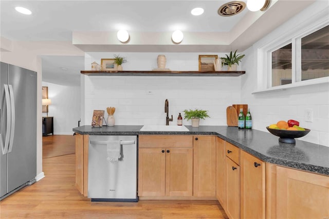 kitchen with dark countertops, light wood-style flooring, stainless steel appliances, open shelves, and a sink