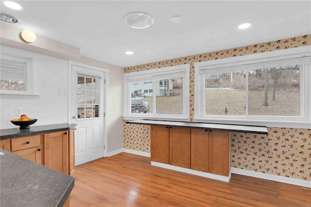 kitchen with baseboards, dark countertops, brown cabinets, light wood-type flooring, and recessed lighting