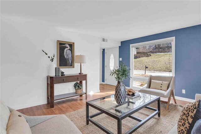 living area featuring light wood-style floors, baseboards, and visible vents