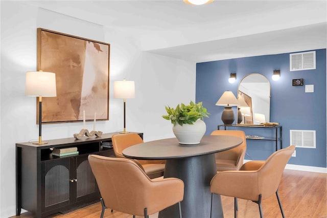 dining room featuring light wood-type flooring, visible vents, and baseboards