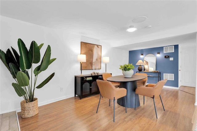 dining space with light wood-style flooring, visible vents, and baseboards