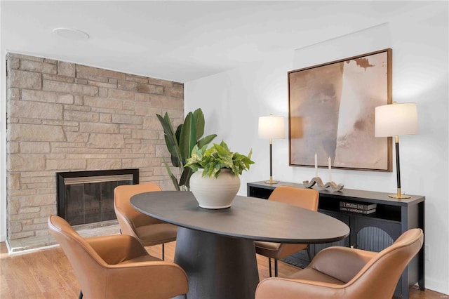 dining area with light wood-type flooring and a fireplace