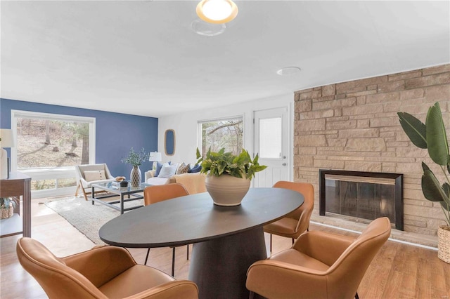 dining space with plenty of natural light, a stone fireplace, and light wood finished floors