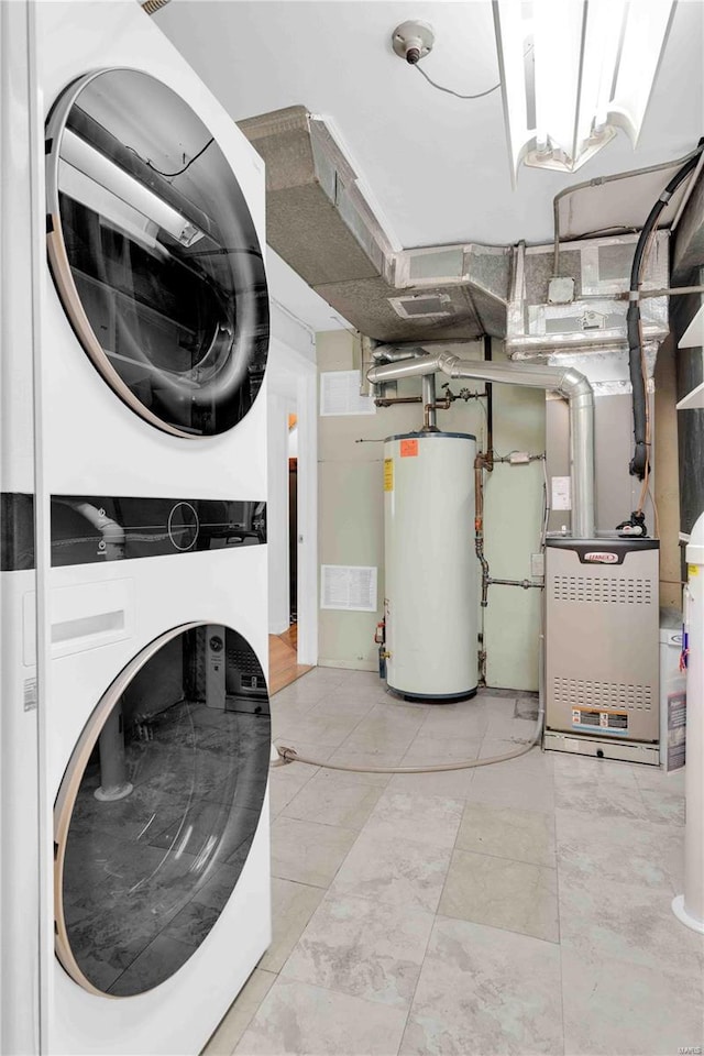 washroom with stacked washer / drying machine, laundry area, water heater, and visible vents