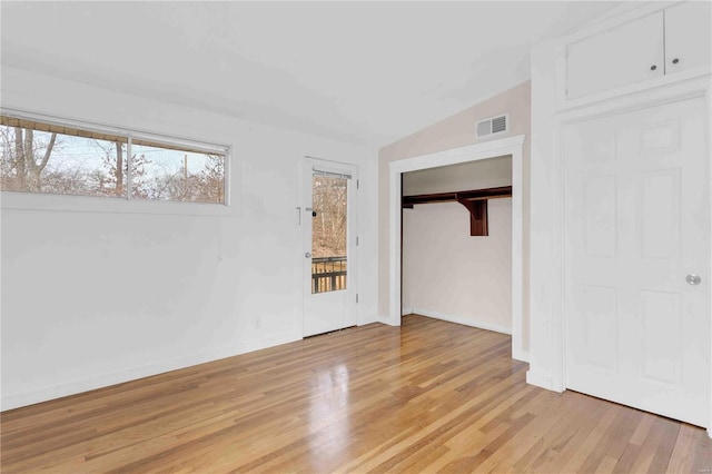 interior space with baseboards, visible vents, lofted ceiling, access to exterior, and light wood-type flooring