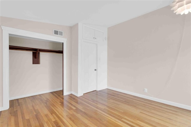 unfurnished bedroom with a closet, visible vents, light wood-style flooring, and baseboards