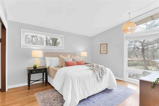 bedroom with multiple windows, wood finished floors, and baseboards