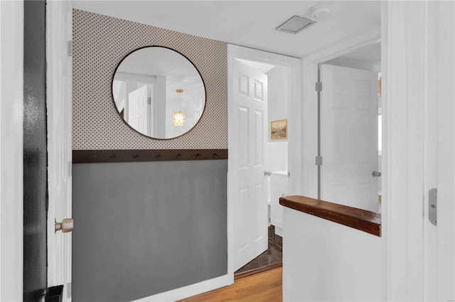 hallway featuring wood finished floors and wallpapered walls