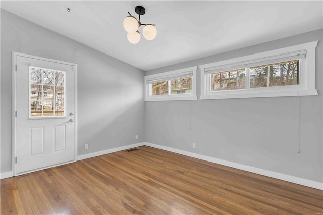 empty room featuring baseboards, visible vents, and wood finished floors