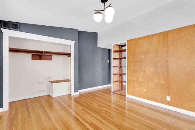 interior space with baseboards, a notable chandelier, visible vents, and wood finished floors