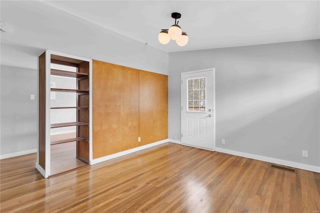 interior space with an inviting chandelier, light wood-style flooring, and baseboards