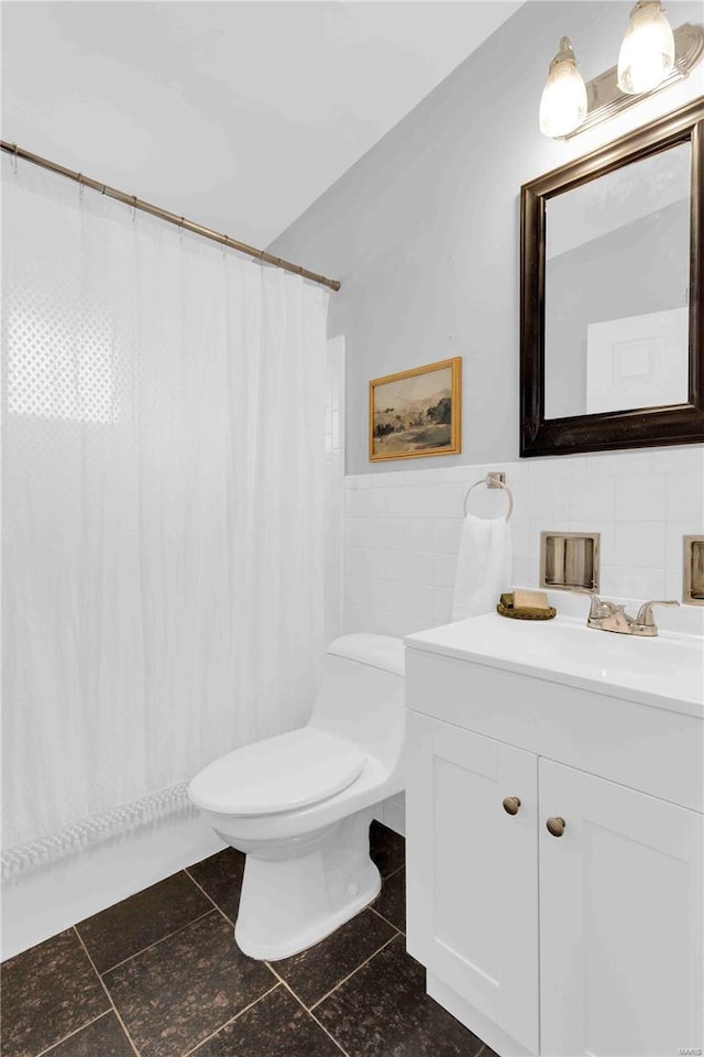 bathroom with toilet, a wainscoted wall, curtained shower, vanity, and tile walls