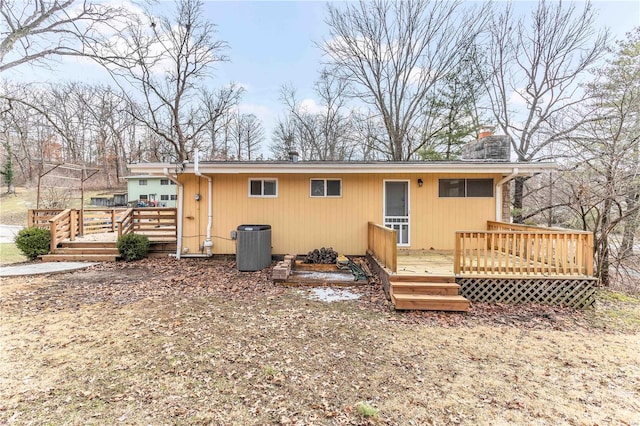 rear view of property featuring a chimney, a wooden deck, and central AC unit