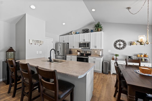 kitchen with stainless steel appliances, light countertops, white cabinetry, a sink, and a kitchen breakfast bar