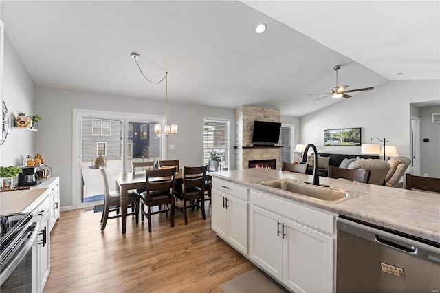 kitchen featuring stainless steel appliances, a sink, white cabinetry, open floor plan, and light countertops