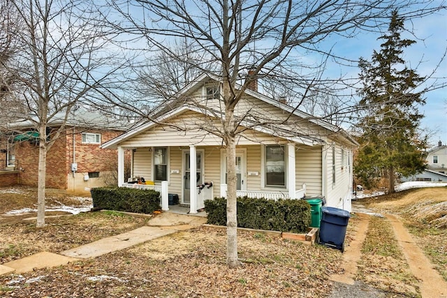 bungalow-style home featuring covered porch and a chimney