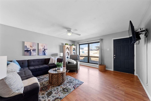 living room featuring a ceiling fan, baseboards, and wood finished floors