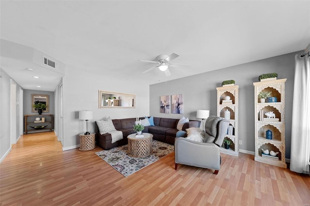 living area with light wood-style floors, ceiling fan, visible vents, and baseboards