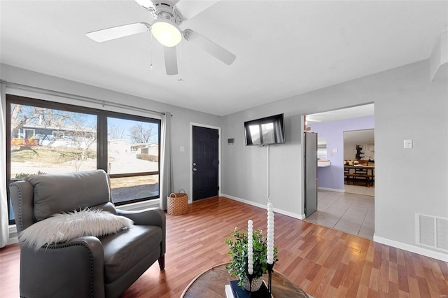 living area with baseboards, visible vents, and light wood finished floors