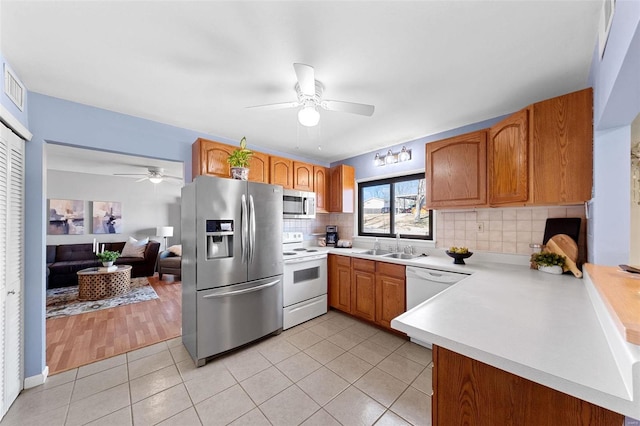 kitchen with light tile patterned floors, decorative backsplash, appliances with stainless steel finishes, light countertops, and a sink