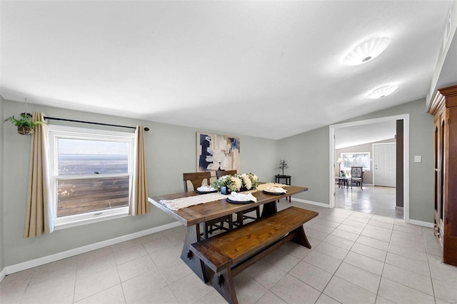 dining area featuring lofted ceiling, baseboards, and light tile patterned floors