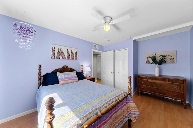 bedroom with a closet, visible vents, ceiling fan, wood finished floors, and baseboards