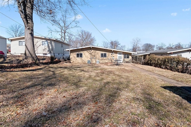 rear view of house with a lawn and fence