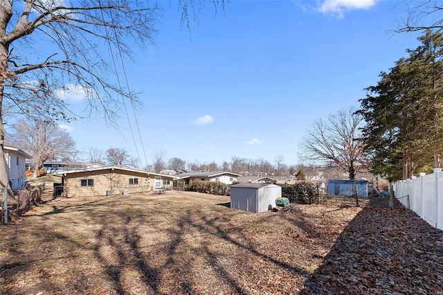 view of yard featuring a storage shed, an outdoor structure, and fence