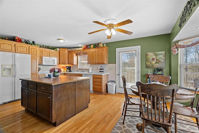 kitchen with light wood-style floors, a wealth of natural light, white appliances, and a center island