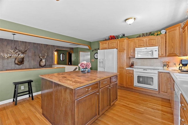 kitchen with white appliances, tasteful backsplash, butcher block countertops, a kitchen island, and light wood-style floors