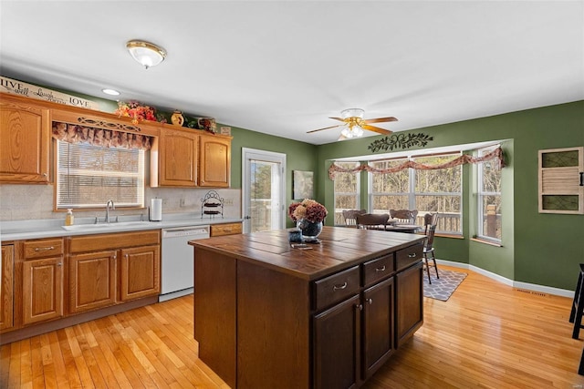 kitchen with plenty of natural light, white dishwasher, wood counters, and a sink