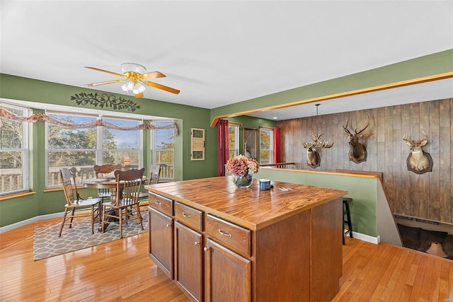 kitchen with light wood finished floors, butcher block countertops, a kitchen island, and brown cabinets