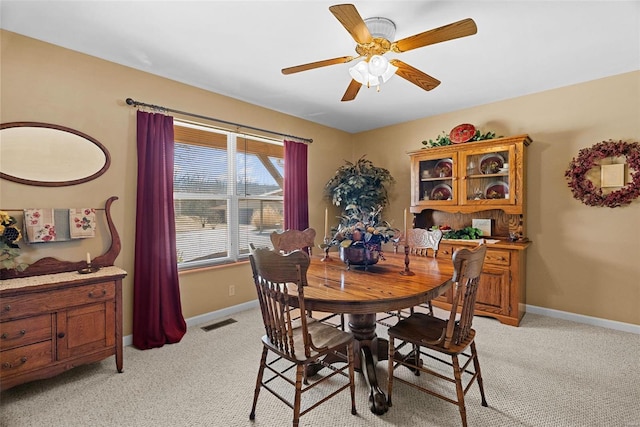 dining space with a ceiling fan, light colored carpet, visible vents, and baseboards