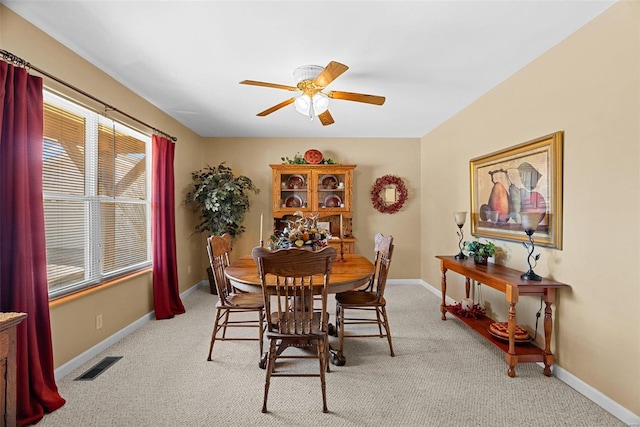 dining room featuring baseboards, a ceiling fan, visible vents, and light colored carpet