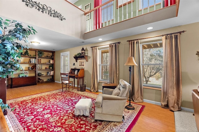 living area with wood finished floors, a towering ceiling, and baseboards