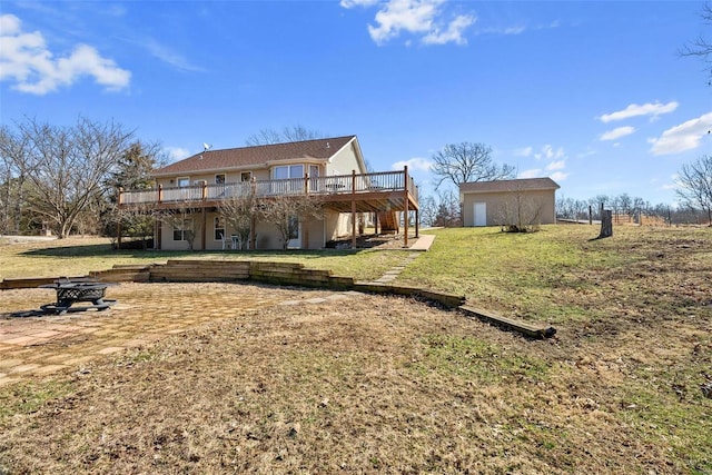 rear view of property featuring a fire pit, a lawn, stairway, a wooden deck, and an outdoor structure