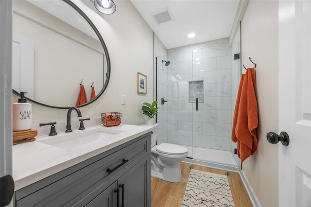 bathroom with toilet, wood finished floors, visible vents, vanity, and a stall shower