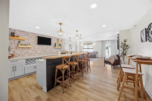 bar featuring hanging light fixtures, light wood-style floors, and recessed lighting