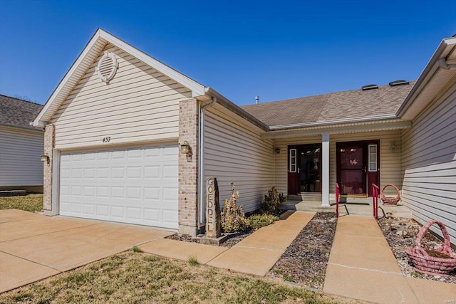 view of front of house featuring a garage, concrete driveway, brick siding, and roof with shingles