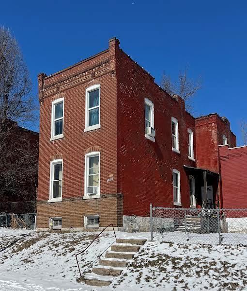 snow covered building with cooling unit and fence