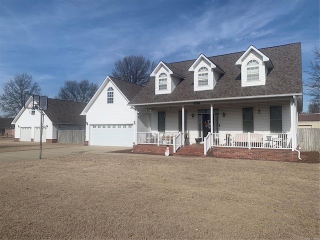 cape cod-style house featuring a porch, an attached garage, driveway, roof with shingles, and a front yard