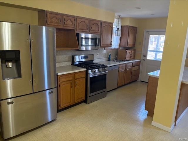 kitchen featuring stainless steel appliances, brown cabinets, light countertops, and light floors