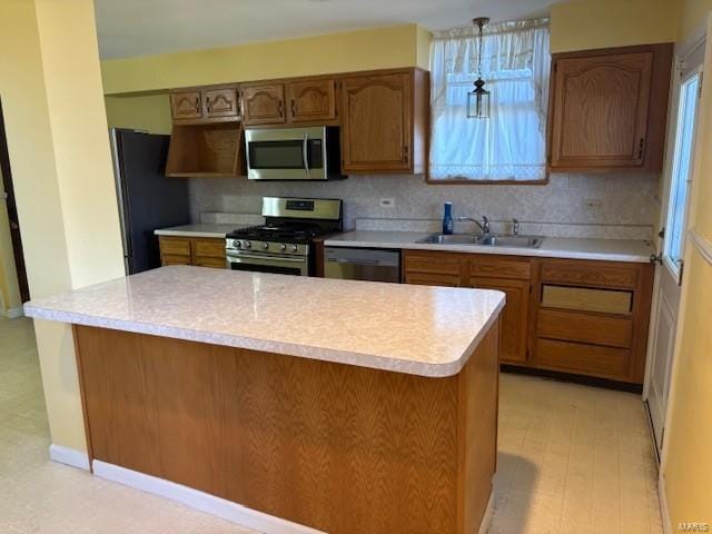 kitchen featuring tasteful backsplash, brown cabinetry, stainless steel appliances, light countertops, and a sink