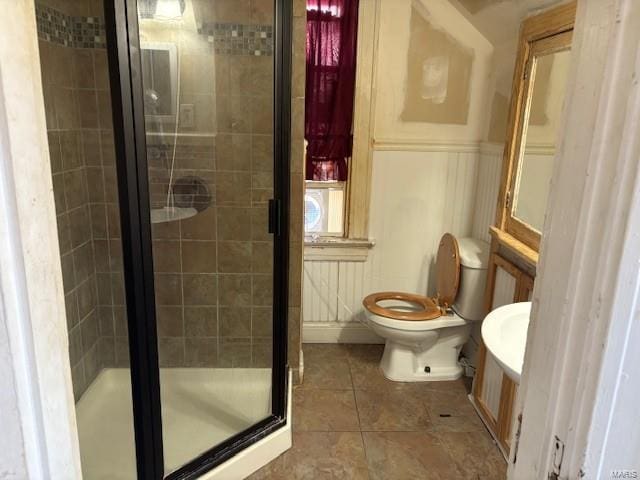 full bath with wainscoting, a shower stall, toilet, and tile patterned floors