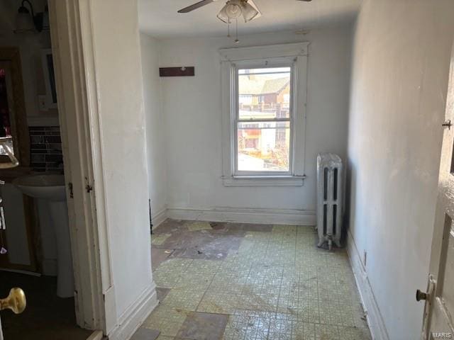 unfurnished room featuring ceiling fan, radiator heating unit, and baseboards