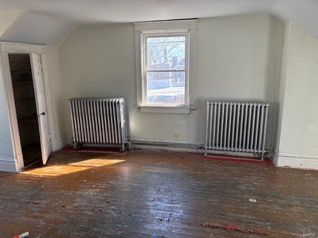 additional living space featuring radiator heating unit, vaulted ceiling, and dark wood-style flooring