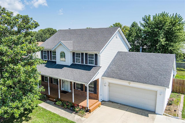 traditional-style house featuring a shingled roof, concrete driveway, an attached garage, a porch, and brick siding