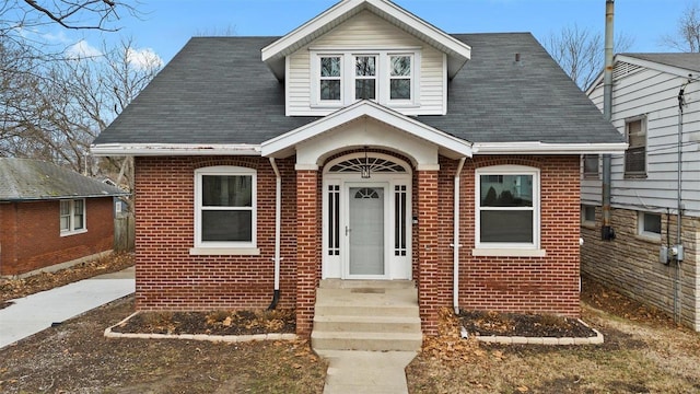 bungalow with a shingled roof and brick siding