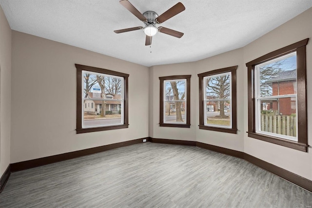 unfurnished room featuring a ceiling fan, a textured ceiling, baseboards, and wood finished floors