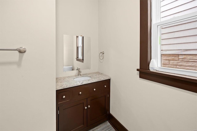 bathroom featuring toilet, vanity, and baseboards